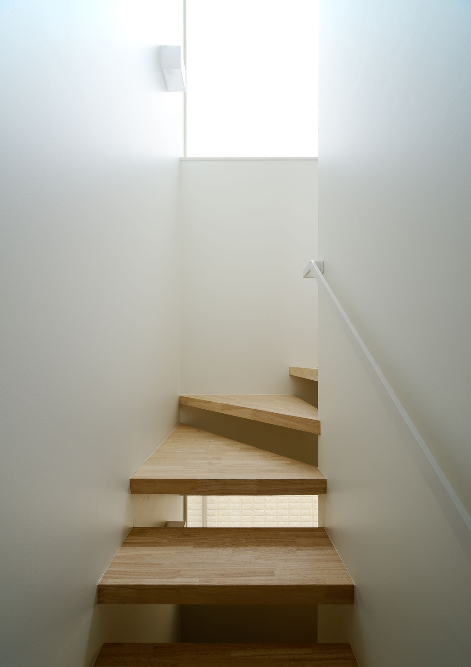 白い手すりが取り付けられたシンプルな木製のスケルトン階段・デザイン住宅