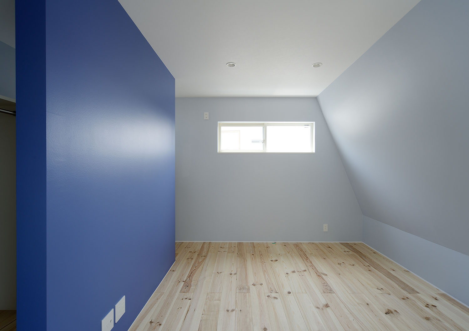 青いアクセントウォールやスリット窓がある母屋下がりの寝室・デザイン住宅