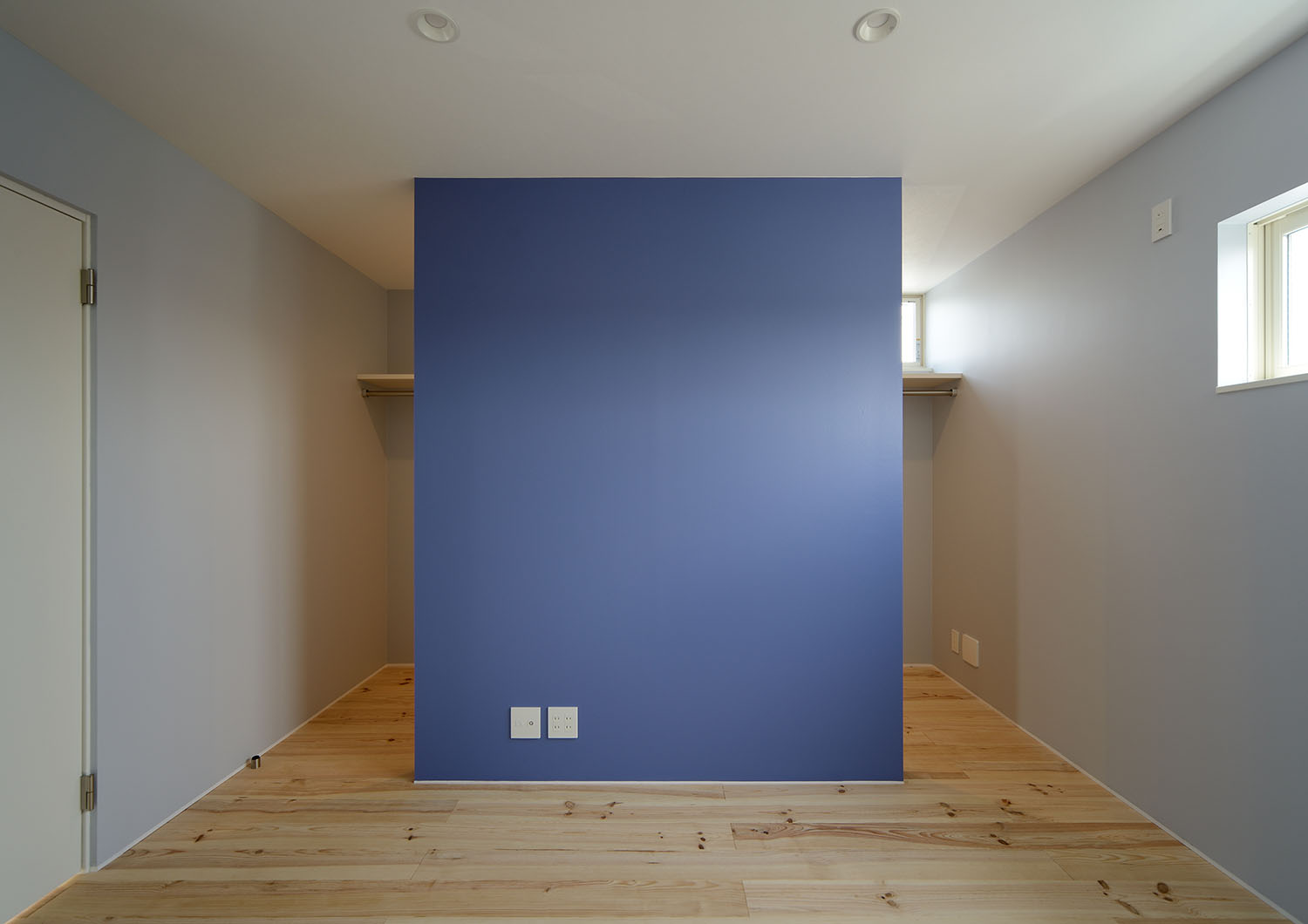 青いアクセントウォールの裏にあるウォークインクローゼット・デザイン住宅