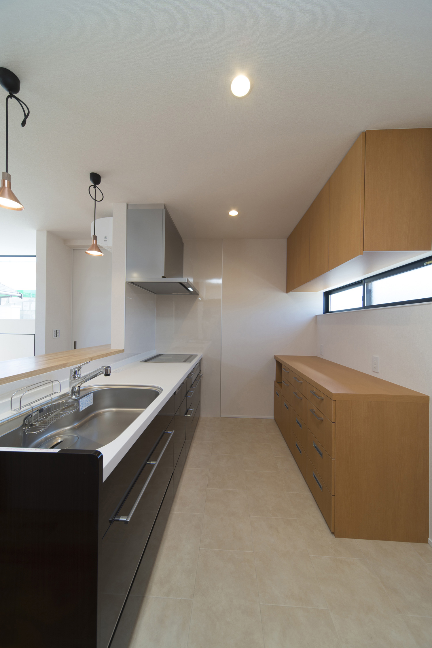 背面に木目のカップボードがあるペニンシュラキッチン・デザイン住宅