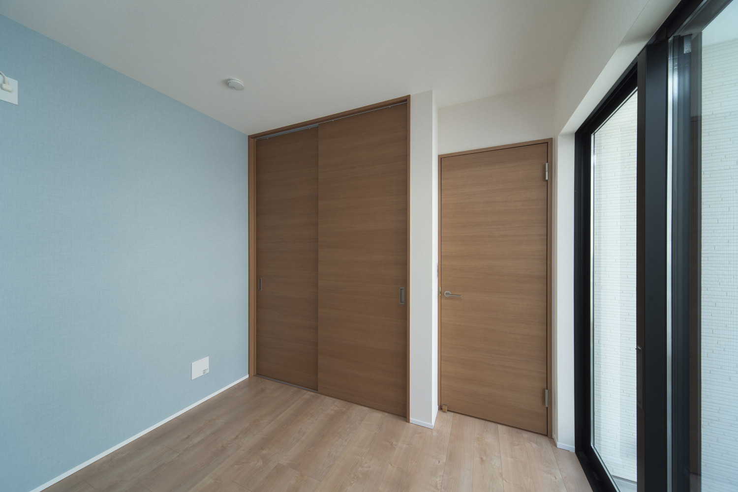 木目のインテリアで、水色のアクセントクロスを取り付けた子供部屋・デザイン住宅