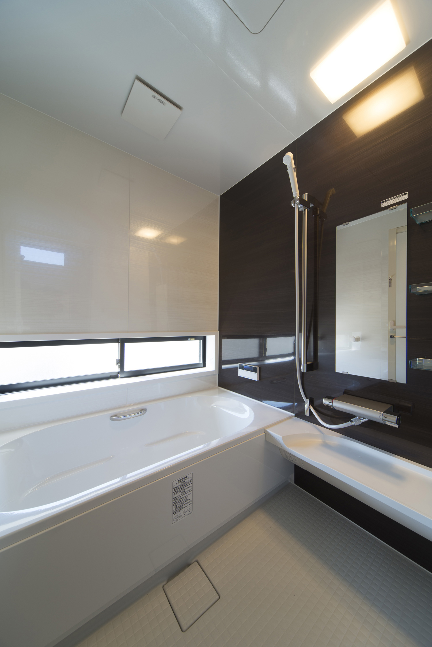 黒いアクセントクロスやスリット窓があるモノトーンの浴室・デザイン住宅