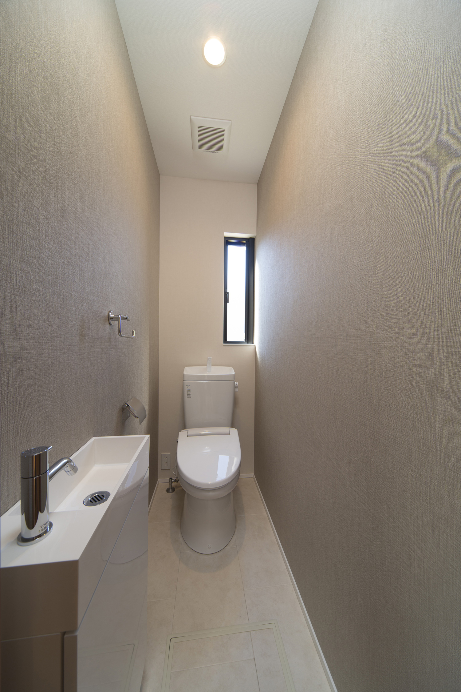 縦長のスリット窓や薄型手洗いがあるシンプルなトイレ・デザイン住宅