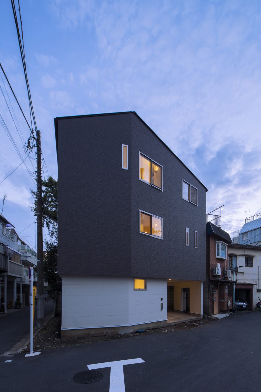 小さな窓から光が漏れる三階建ての家・デザイン住宅