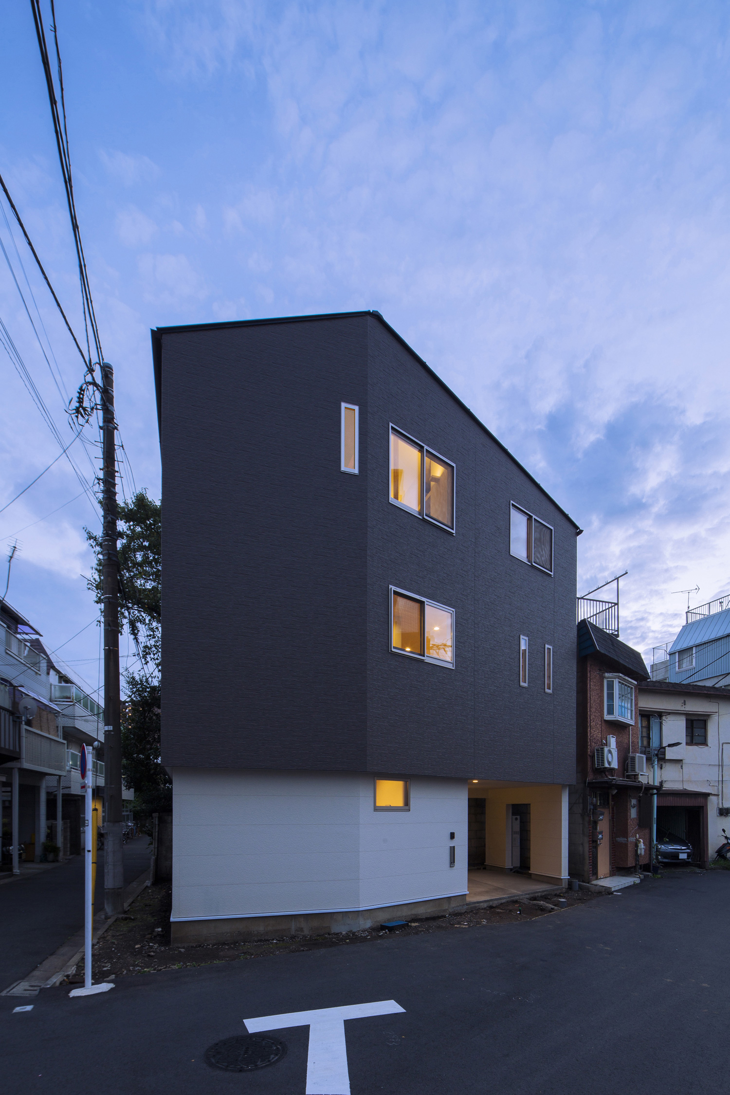 小さな窓から光が漏れる三階建ての家・デザイン住宅