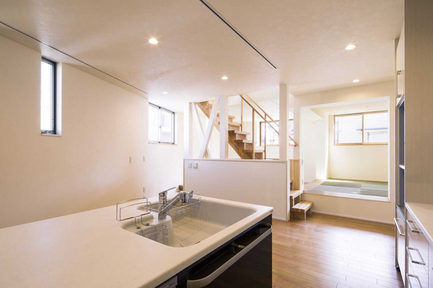 キッチンから畳スペースが見える、中央に階段があるLDK・デザイン住宅