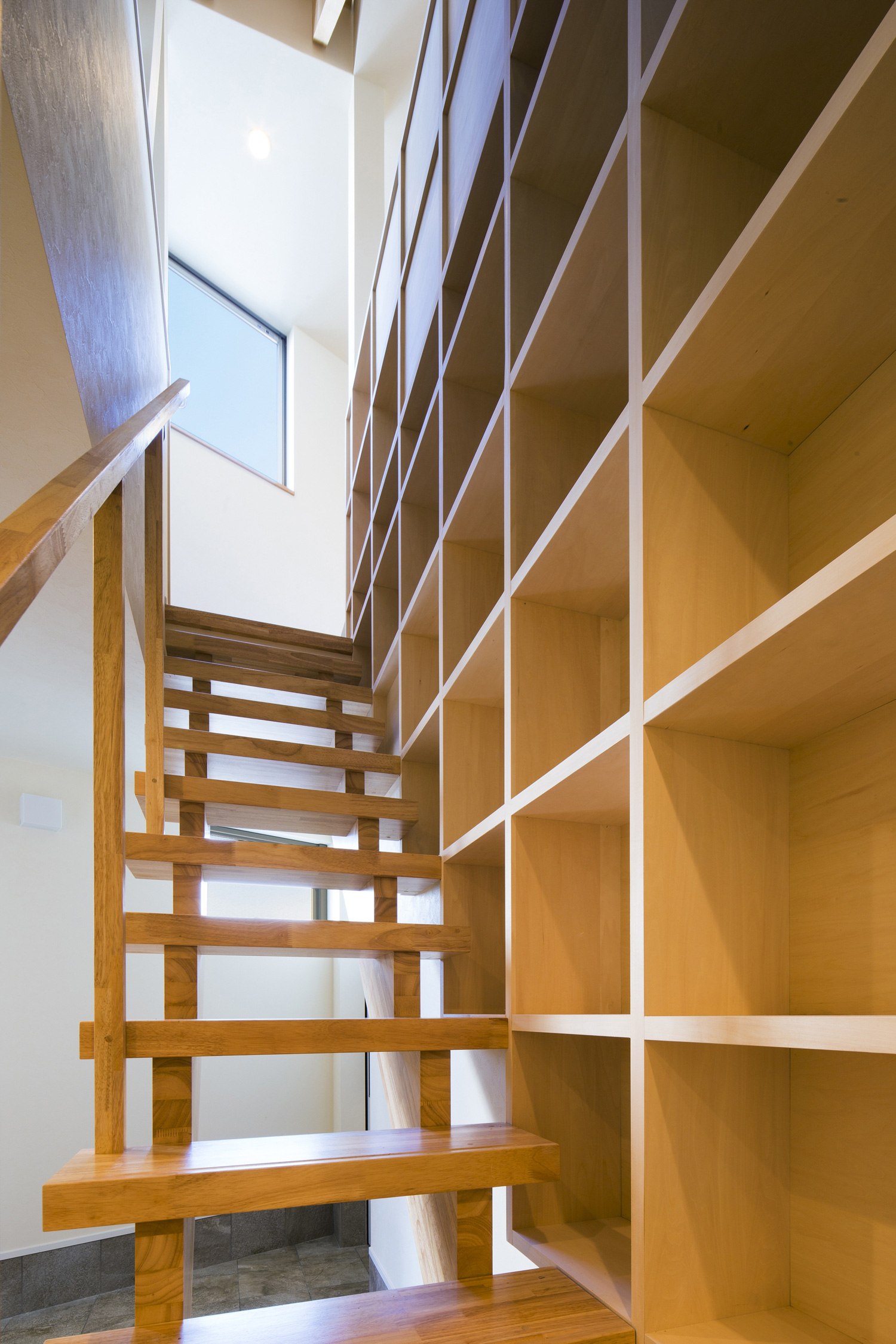 壁に収納棚が取り付けられた木製のスケルトン階段・デザイン住宅