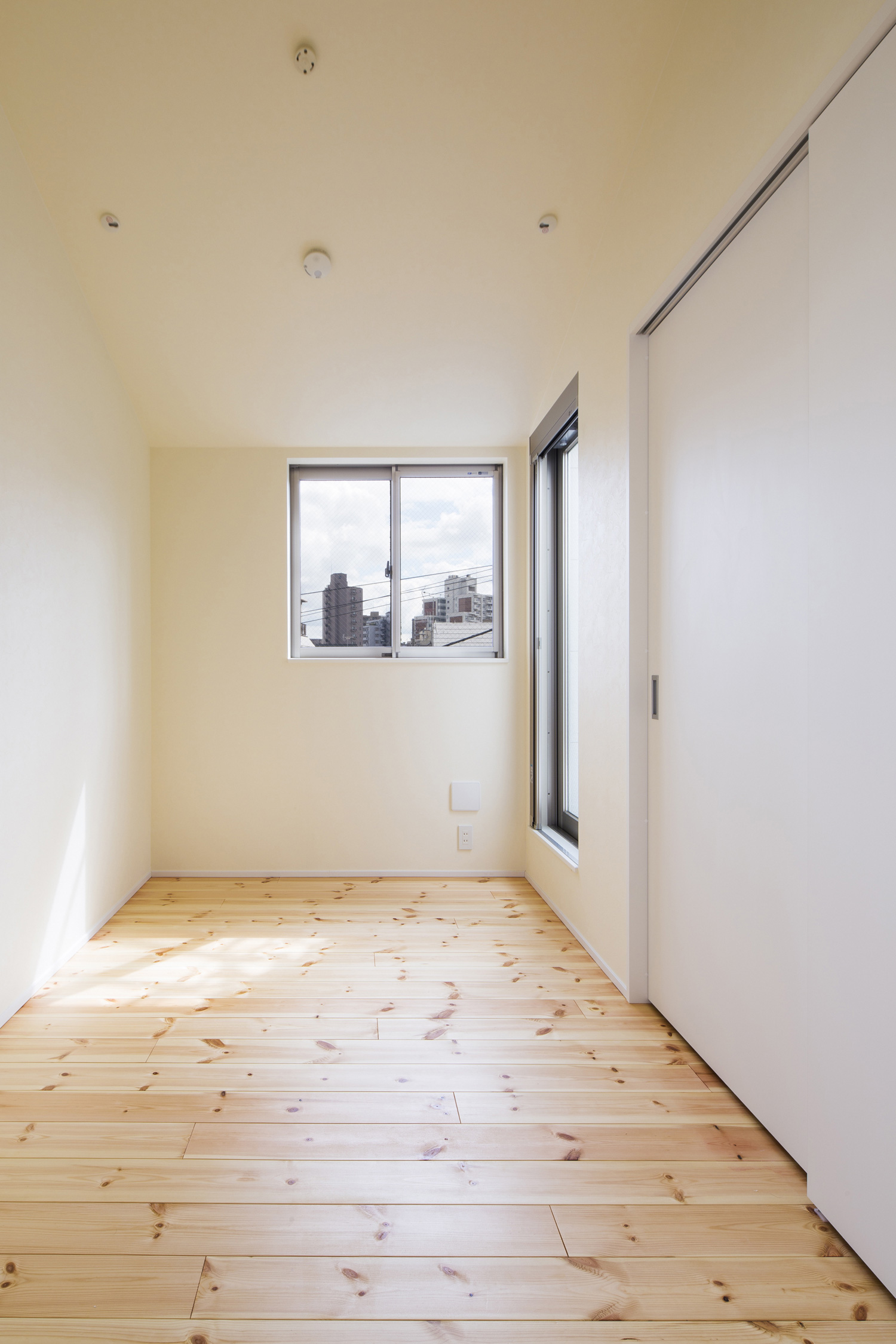 小さな窓があるシンプルなフローリングの寝室・デザイン住宅