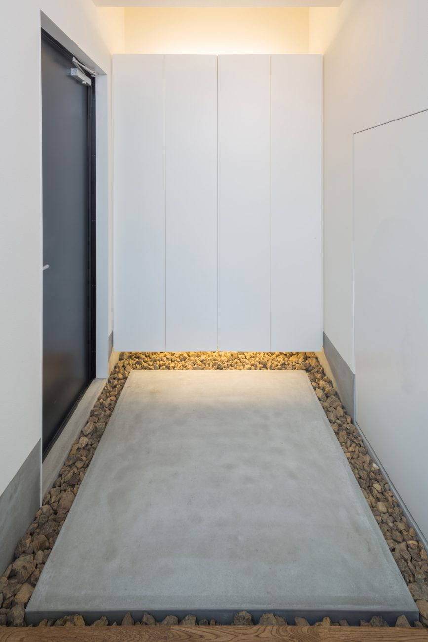 浮いたデザインの間接照明付きのシューズボックスがあるおしゃれな玄関・デザイン住宅