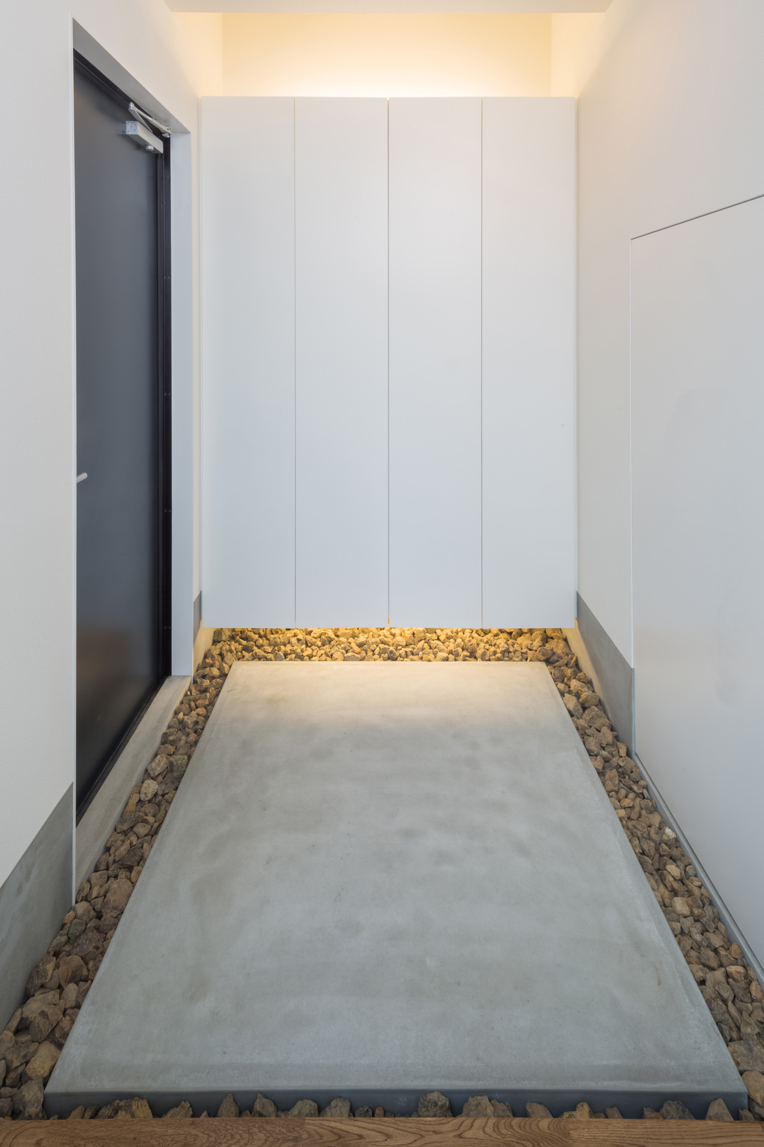 浮いたデザインの間接照明付きのシューズボックスがあるおしゃれな玄関・デザイン住宅