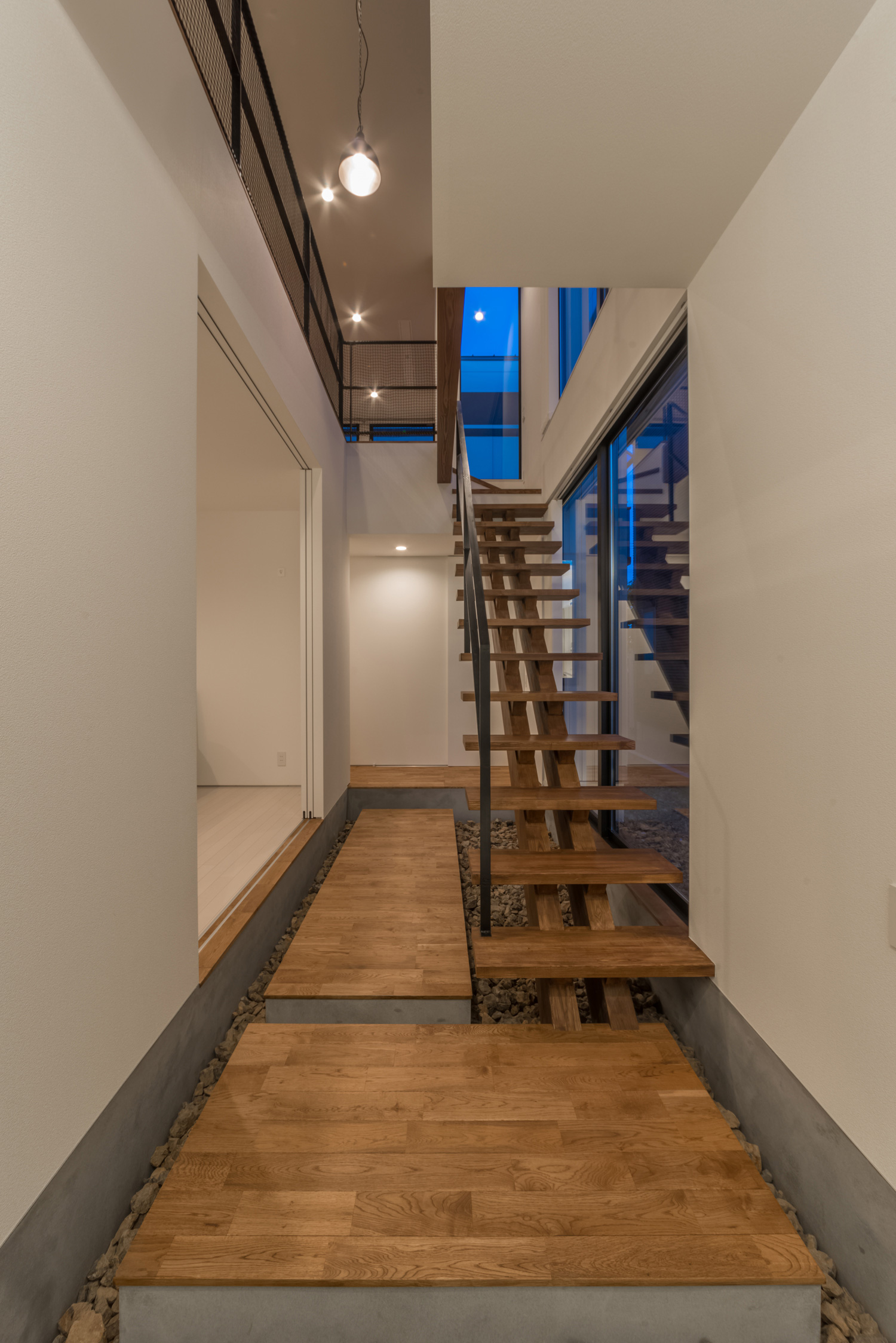 木製のスケルトン階段がある吹き抜けの廊下・デザイン住宅