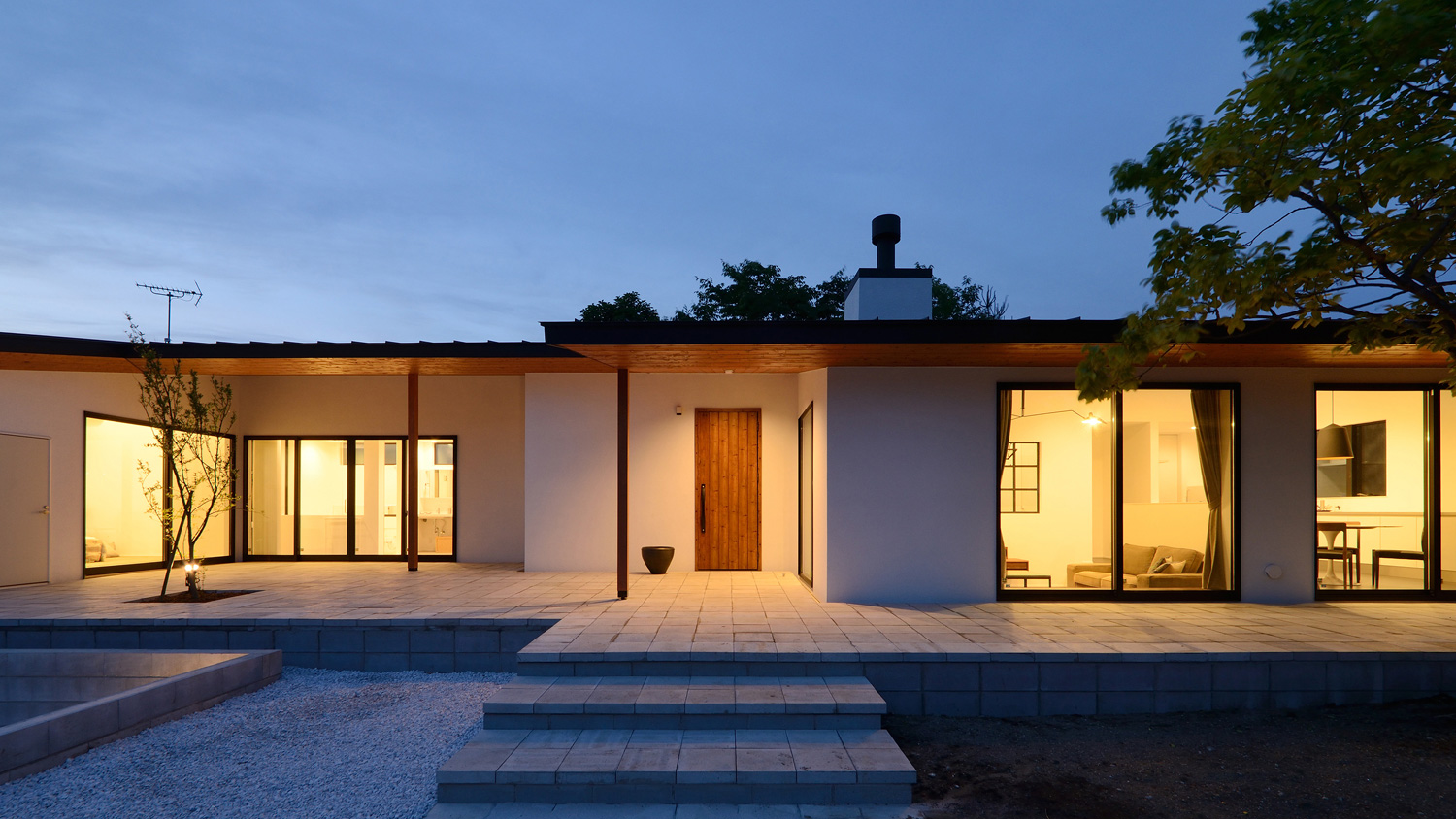 大きな窓から光が漏れるシンプルな外観の平屋・デザイン住宅