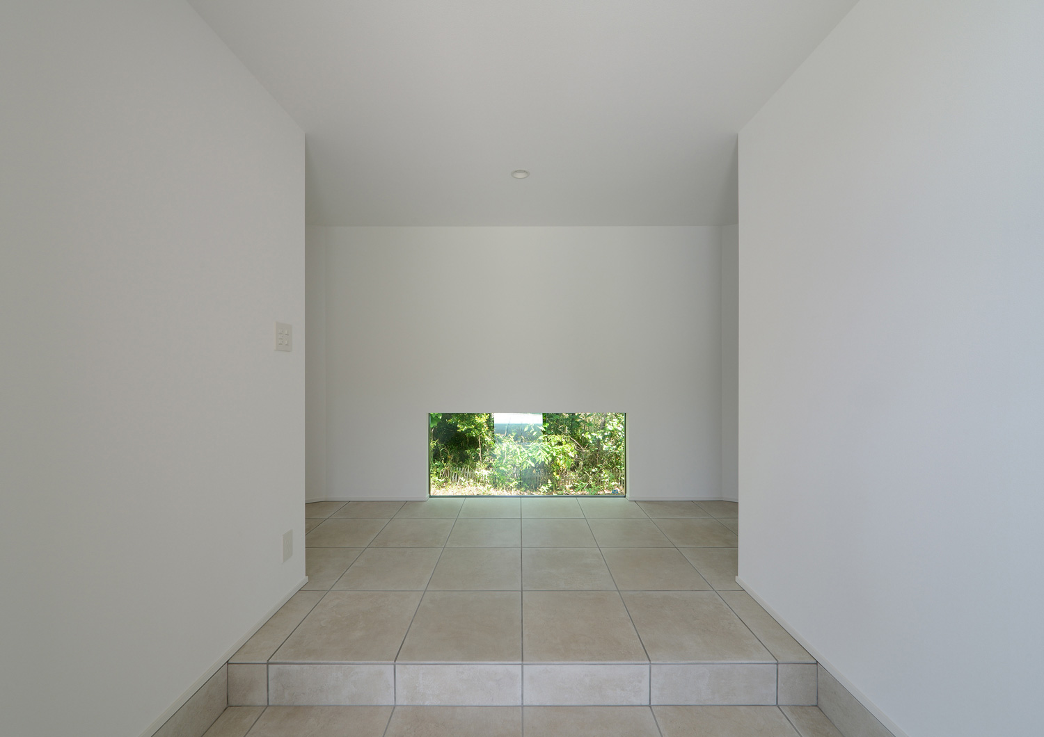 正面に緑が見える地窓があるシンプルな玄関・デザイン住宅