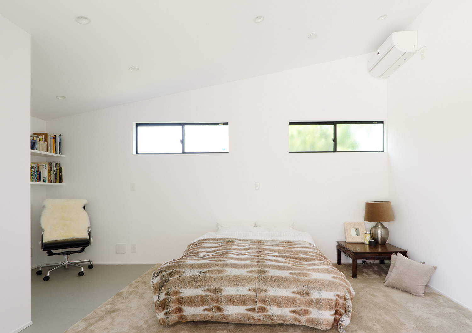 サイドテーブルや本棚があるシンプルで広い寝室・デザイン住宅