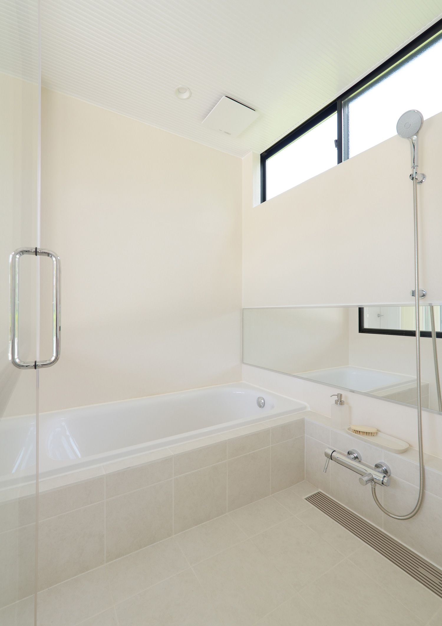 白いタイルの床でスリット窓があるシンプルな浴室・デザイン住宅