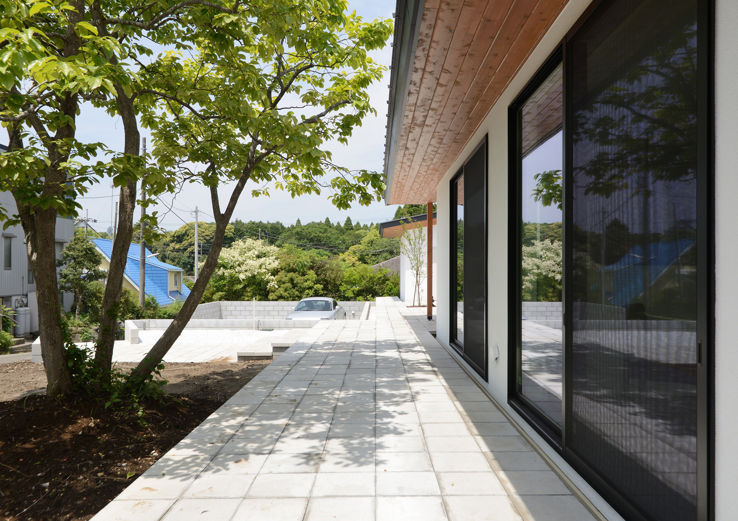 大きなシンボルツリーのある庭に面した軒天井のあるテラス・デザイン住宅