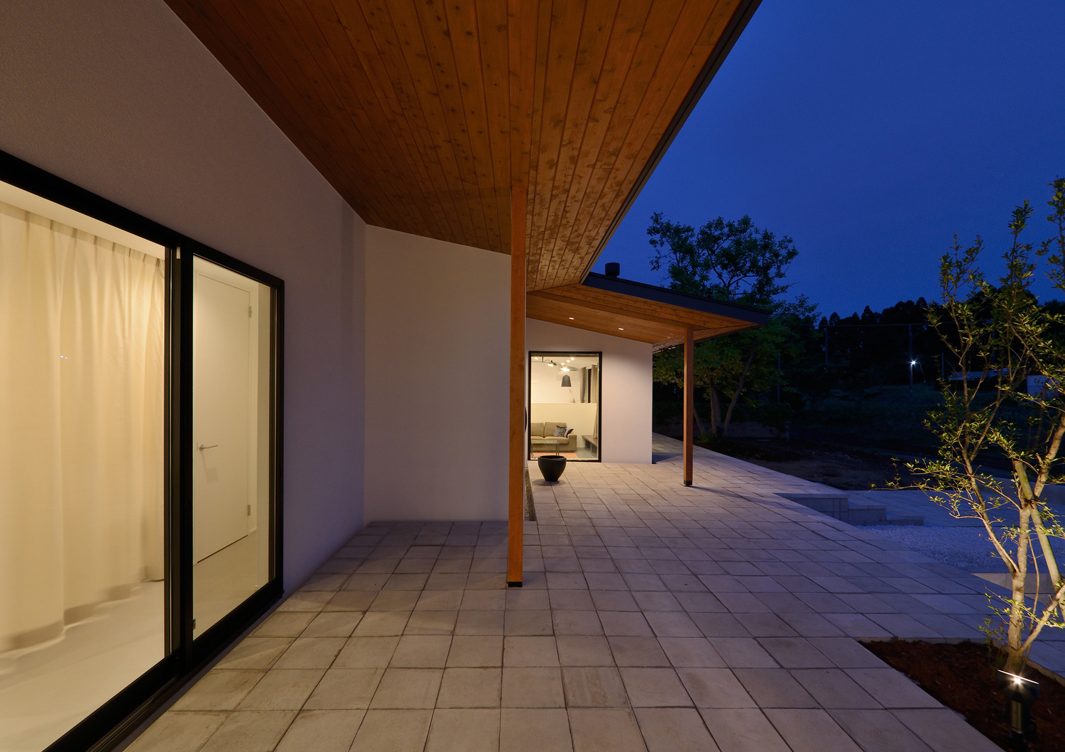 大きな窓から光が漏れる軒天井のテラス・デザイン住宅