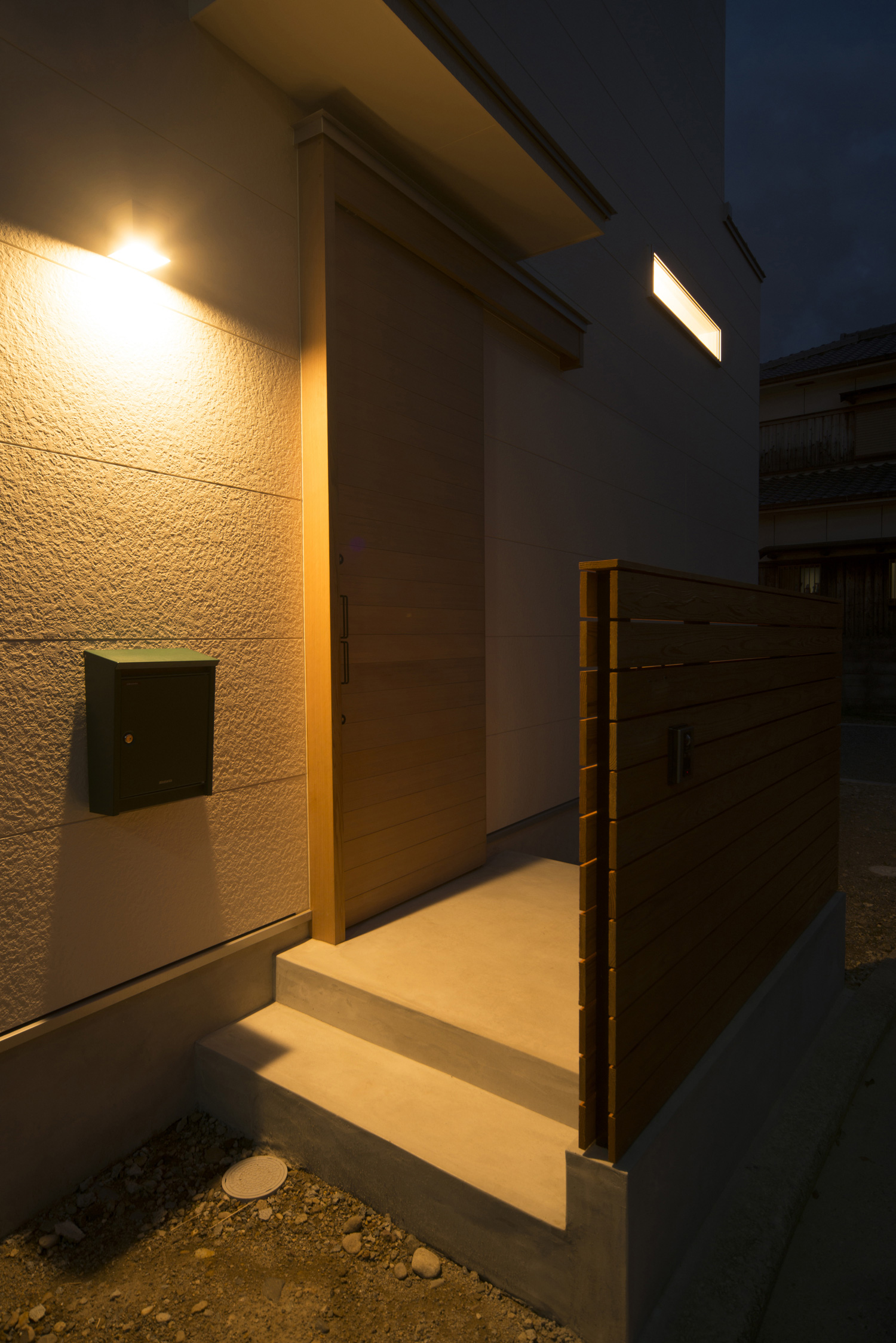 壁に間接照明が取り付けられた玄関アプローチ・デザイン住宅