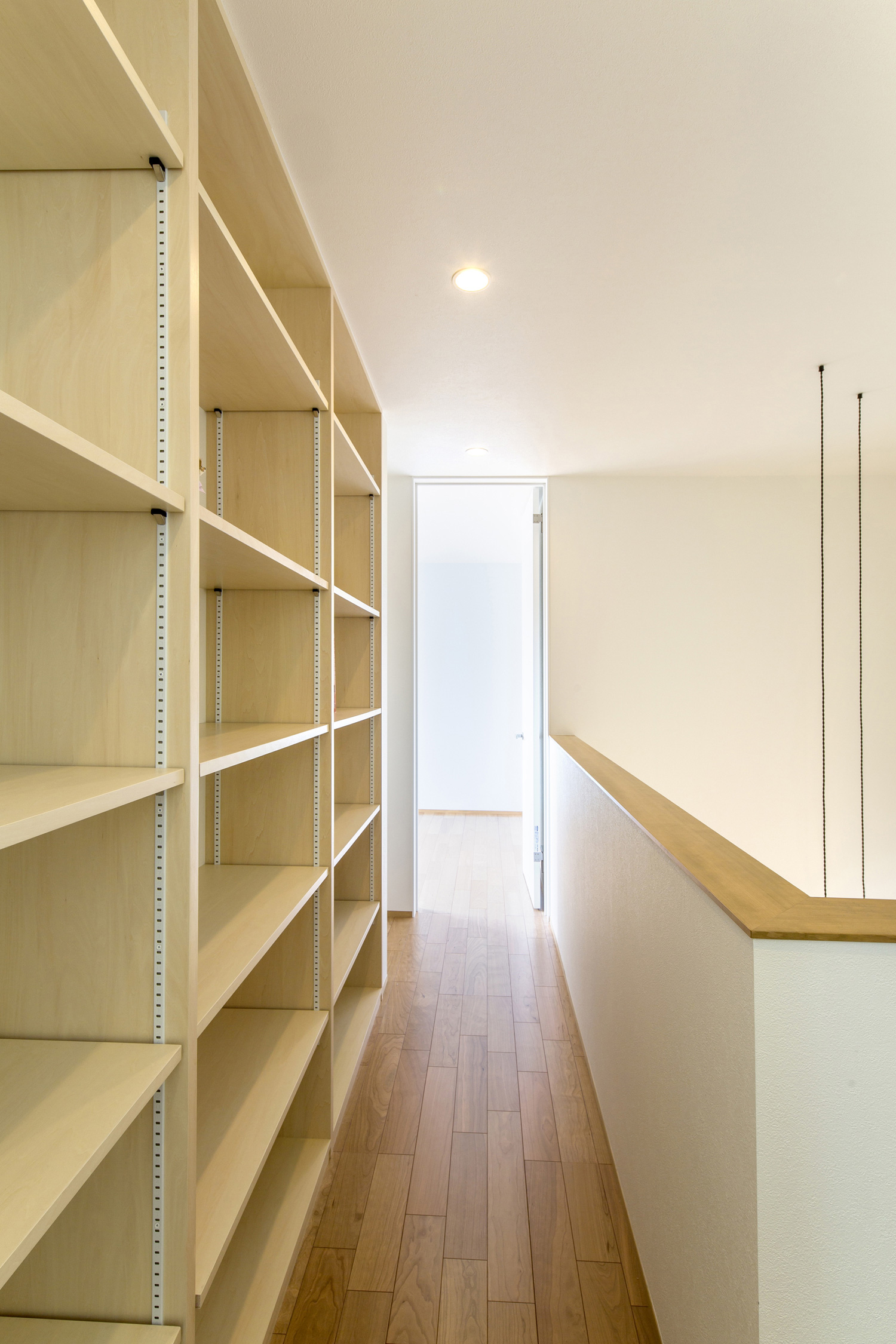壁際に収納棚を取り付けたシンプルな廊下・デザイン住宅