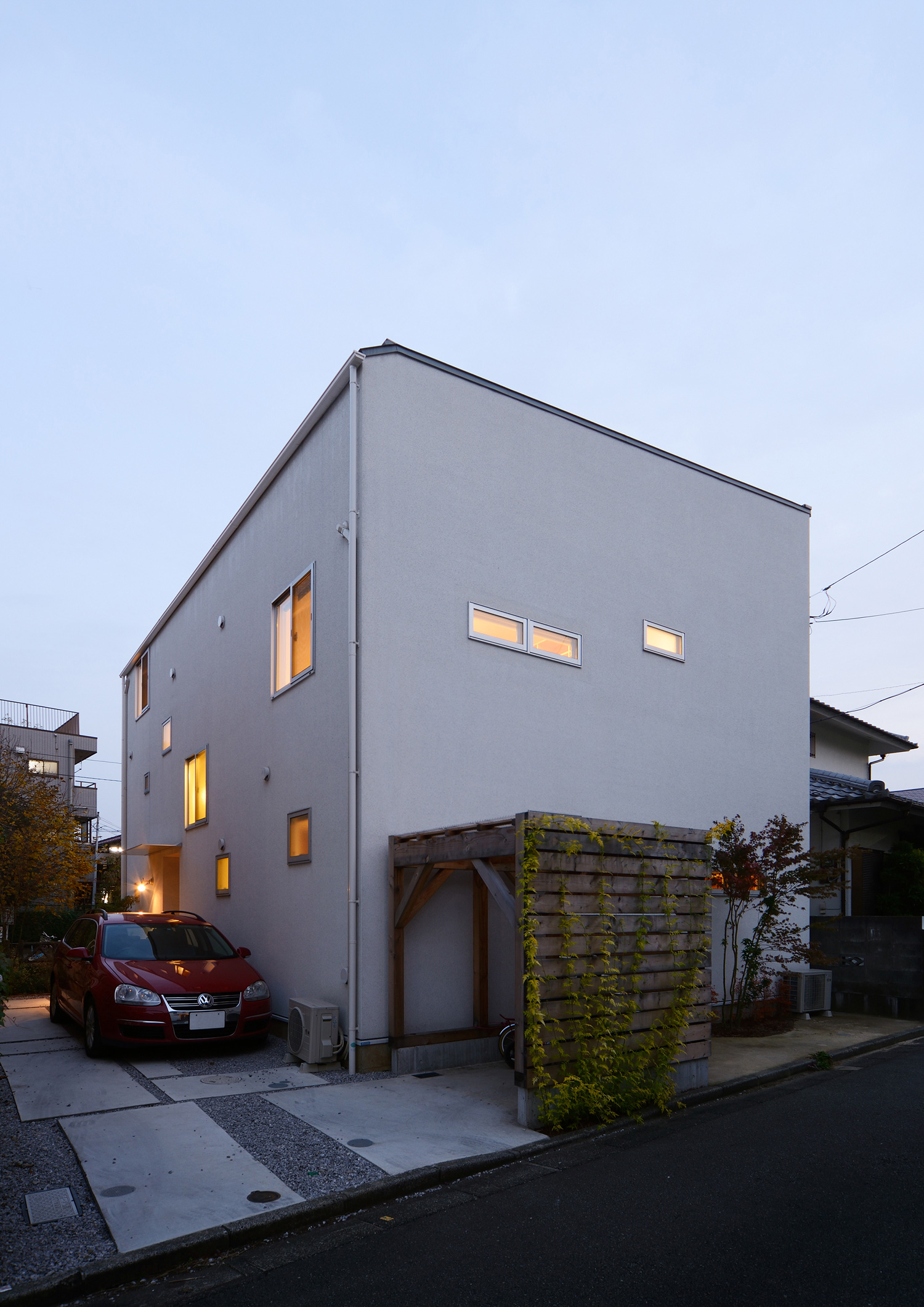 小さな窓から光が漏れるシンプルな白い外壁の家・デザイン住宅