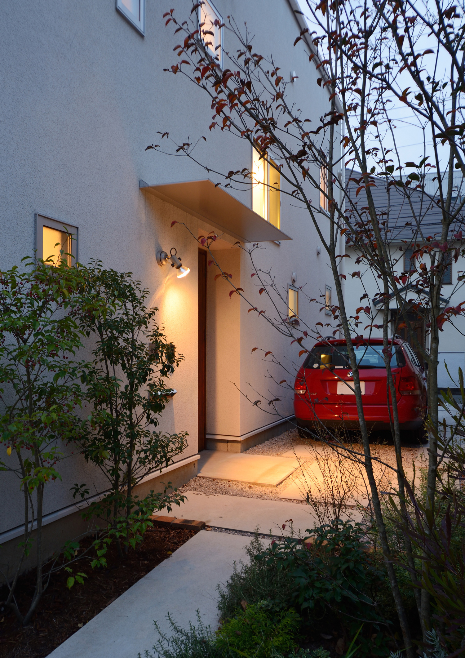 壁に照明を取り付けたシャープな庇がある玄関ポーチ・デザイン住宅