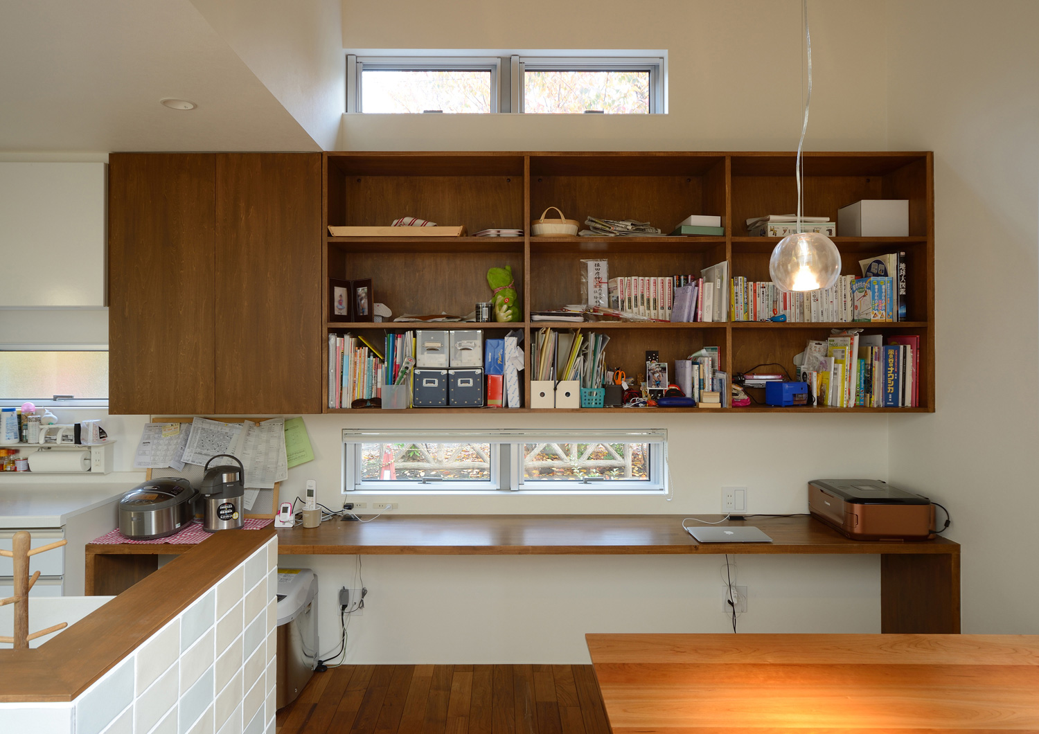 壁付けの本棚と壁付けデスクがあるLDKと一体になったワークスペース・デザイン住宅