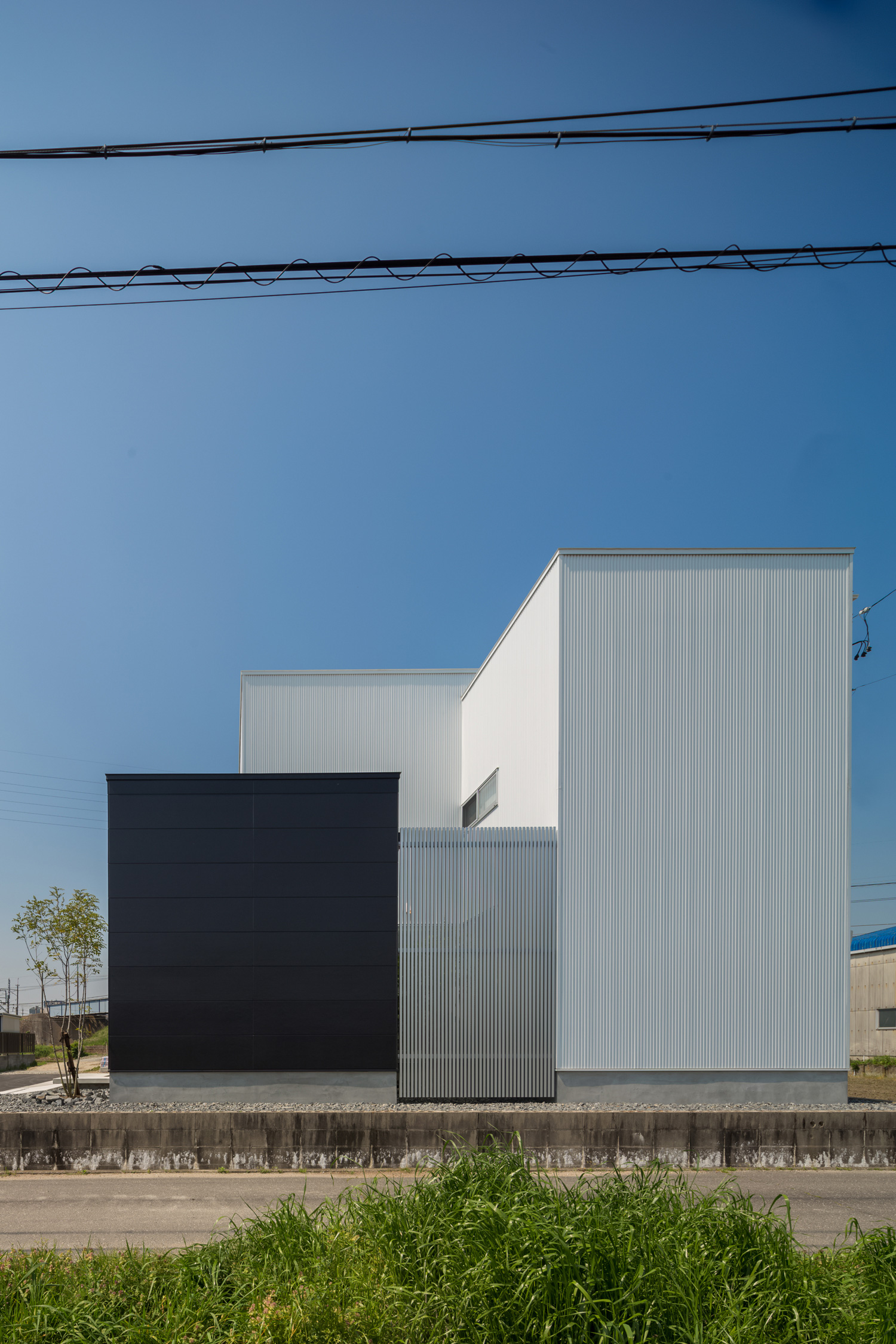 シルバーのルーバーが取り付けられたモノトーンのシンプルな外観の家・デザイン住宅