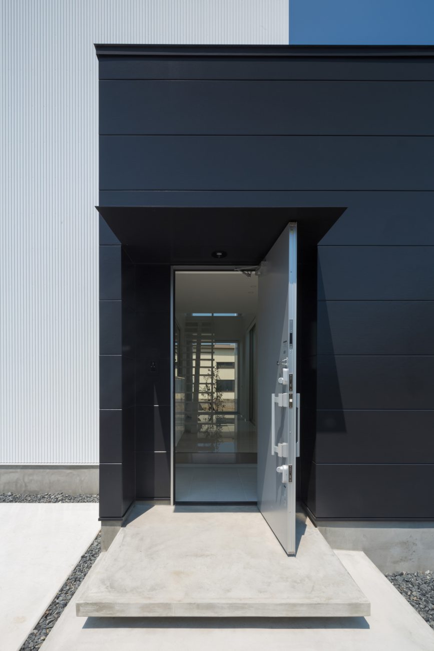 玄関扉を開けて室内が見えるコンクリートの玄関ポーチ・デザイン住宅