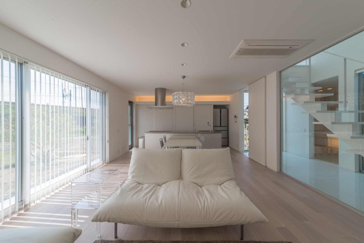 ブラインドを取り付けた大きな窓がある白でまとめられたLDK・デザイン住宅