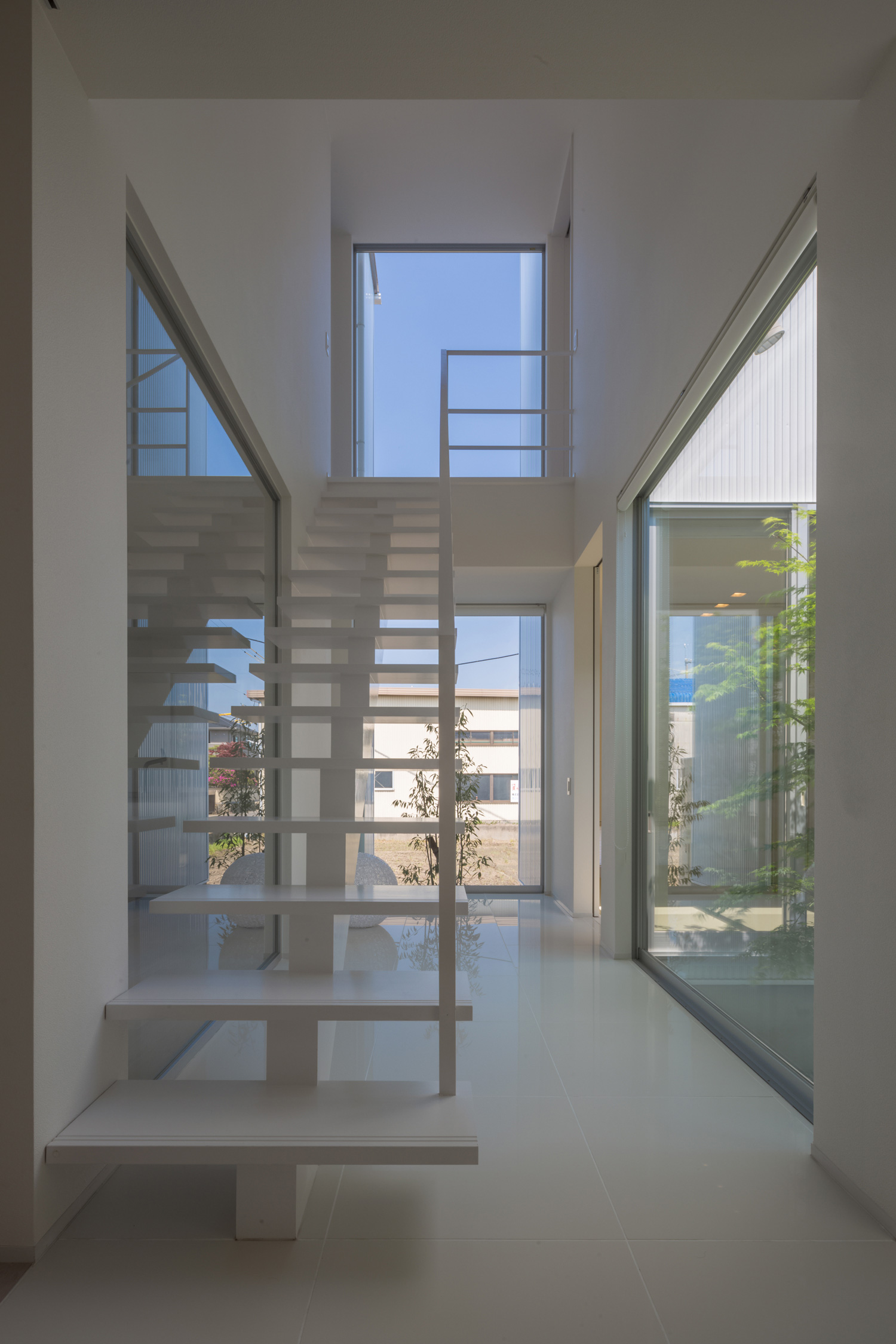 窓に囲まれた、スケルトン階段のある吹き抜けの廊下・デザイン住宅