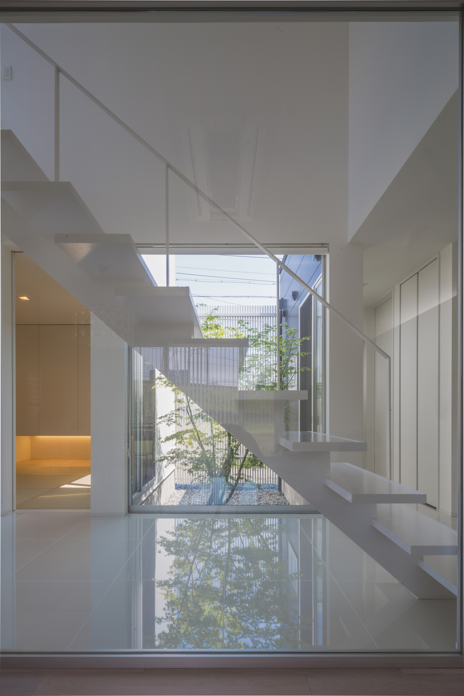スケルトン階段越しに中庭の見える窓がある開放的なデザイン・デザイン住宅