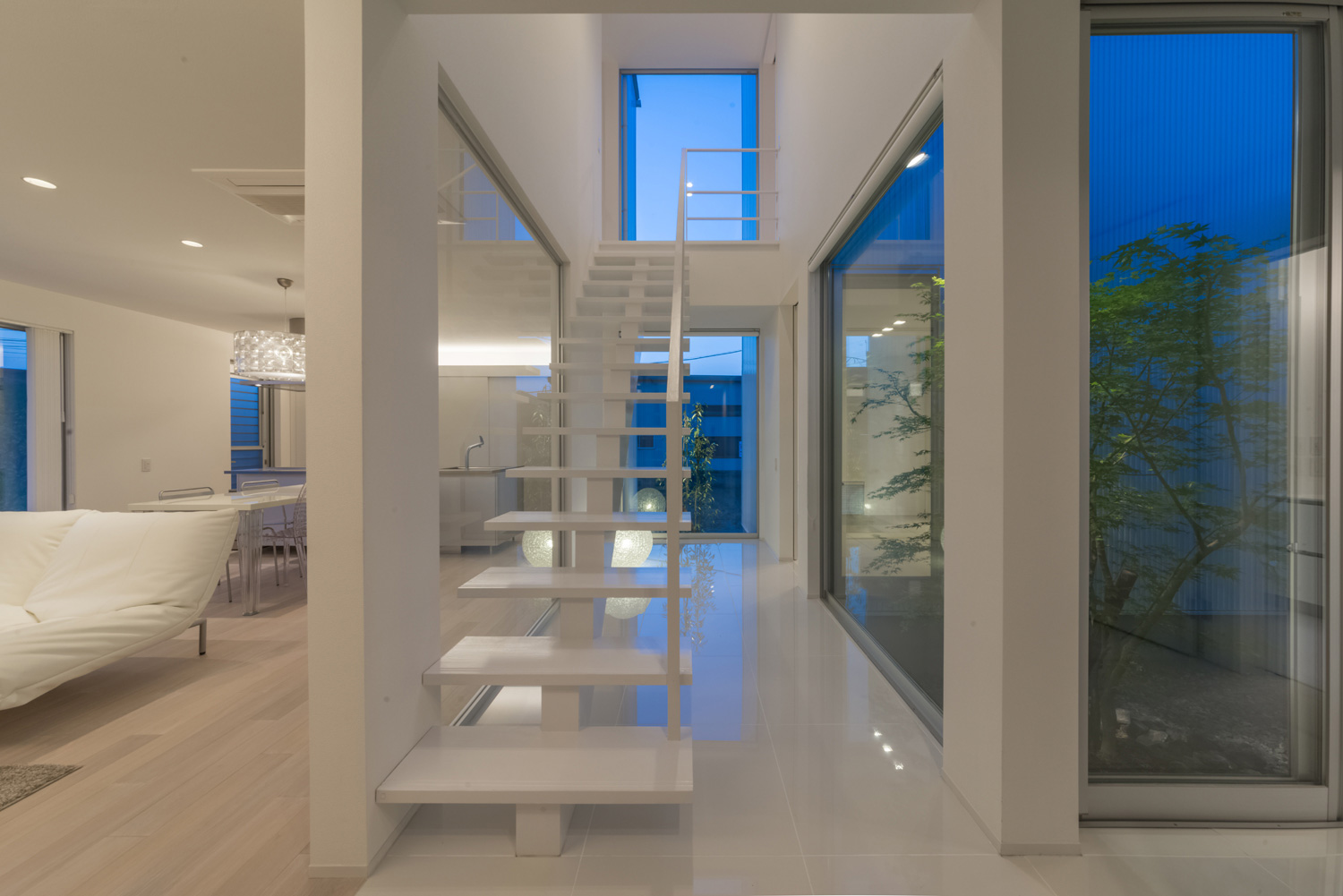 スケルトン階段下に間接照明を取り付けた白一色の廊下・デザイン住宅