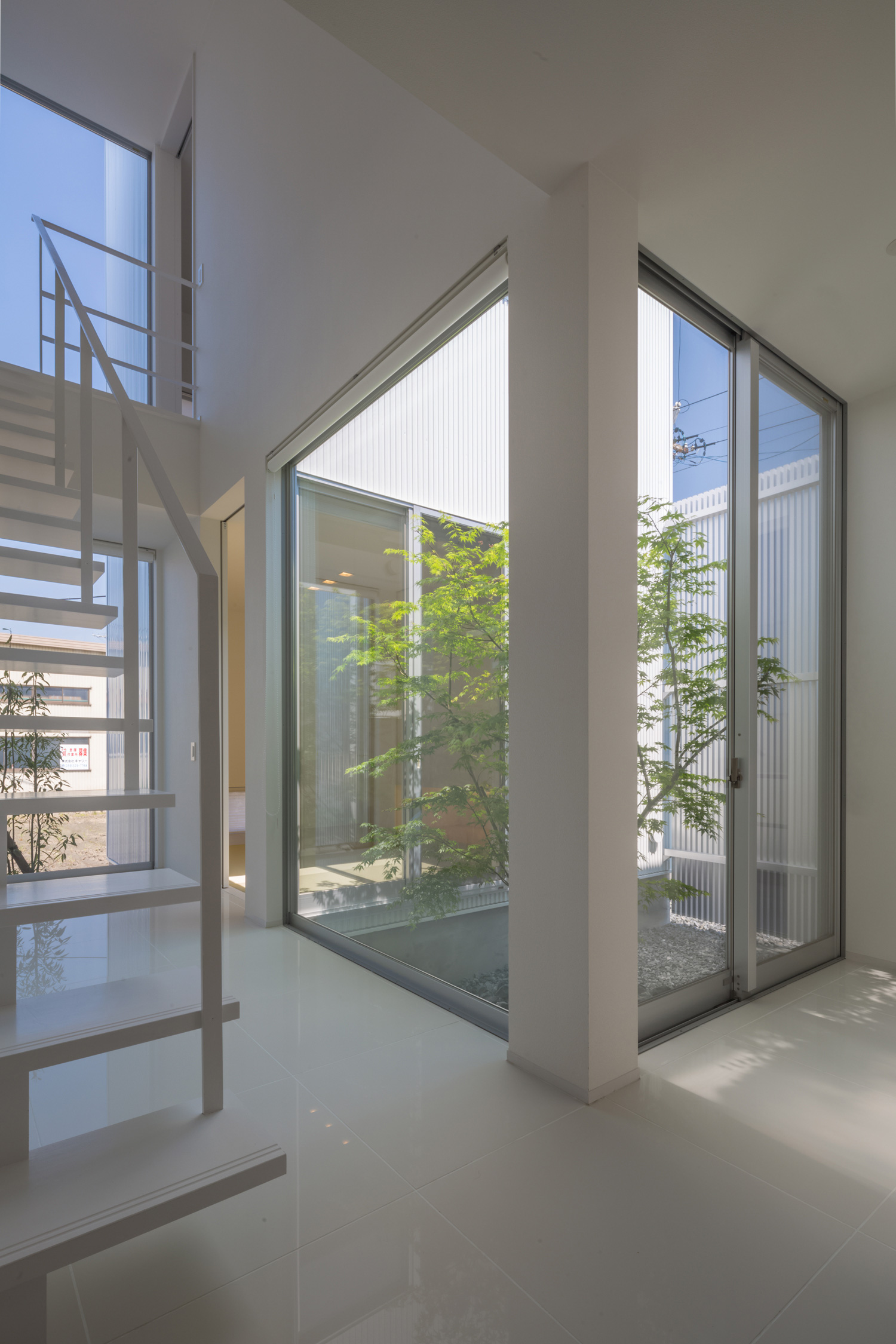 中庭を囲むように窓を取り付けた白い床の廊下・デザイン住宅
