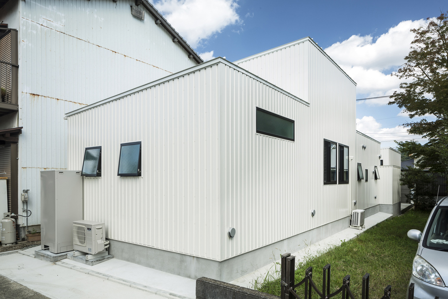 白い金属の外壁に小さい窓が取り付けられた工場のような家・デザイン住宅 注文住宅・デザイン住宅建築実例_『CASE437 LG』_外観