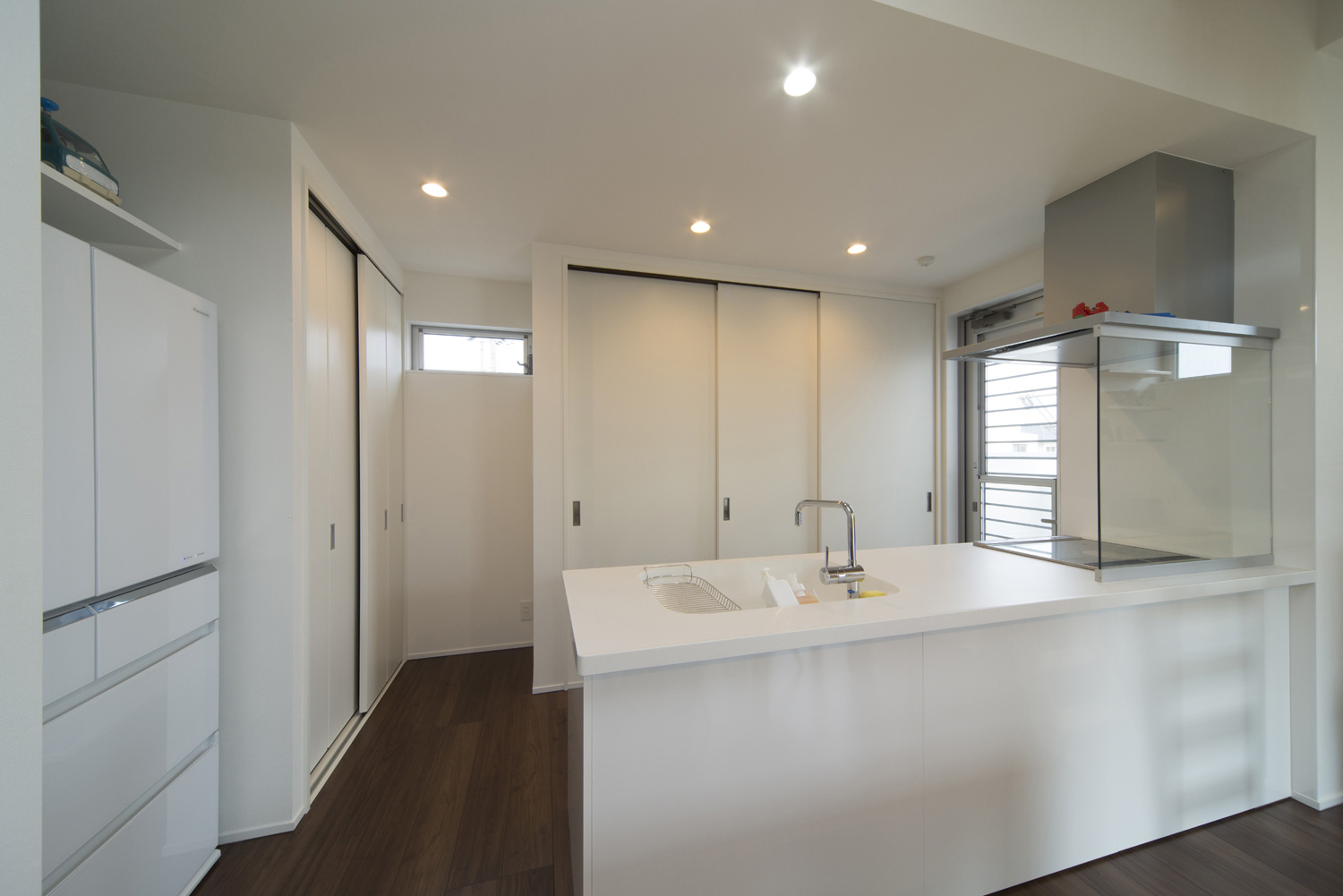 扉付きのカップボードがある白いペニンシュラキッチン・デザイン住宅 注文住宅・デザイン住宅建築実例_『CASE445 ひとときの家』_キッチン