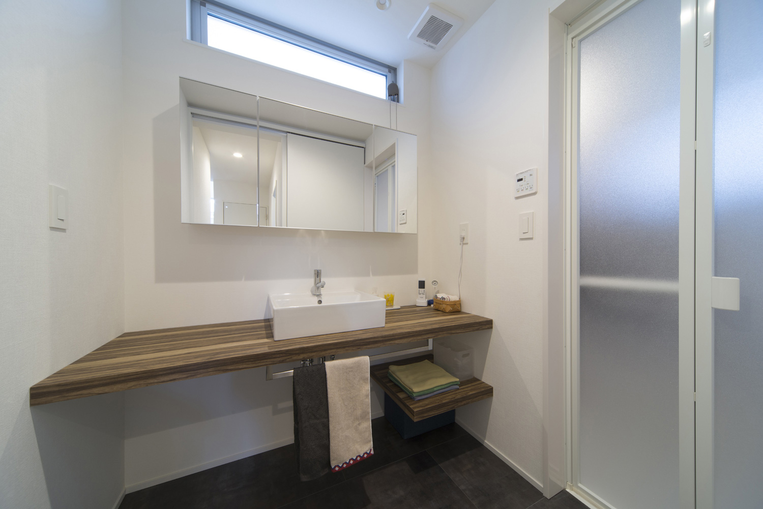 広々とした木の洗面台があるシンプルな洗面所・デザイン住宅 注文住宅・デザイン住宅建築実例_『CASE445 ひとときの家』_浴室・洗面所