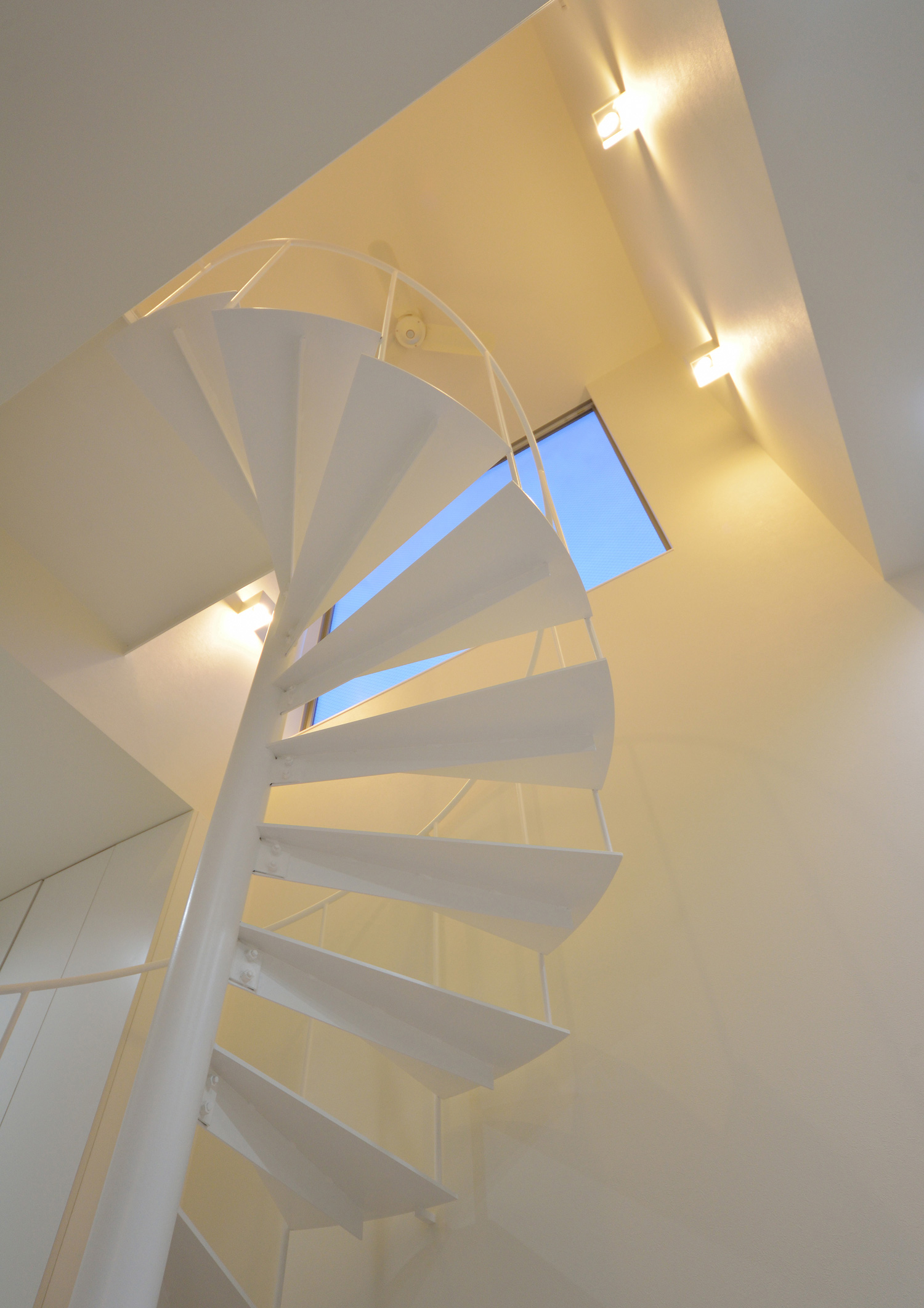 壁に照明が取り付けられた螺旋階段の吹き抜けの階段室・デザイン住宅 注文住宅・デザイン住宅建築実例_『CASE451 台形の家』_階段