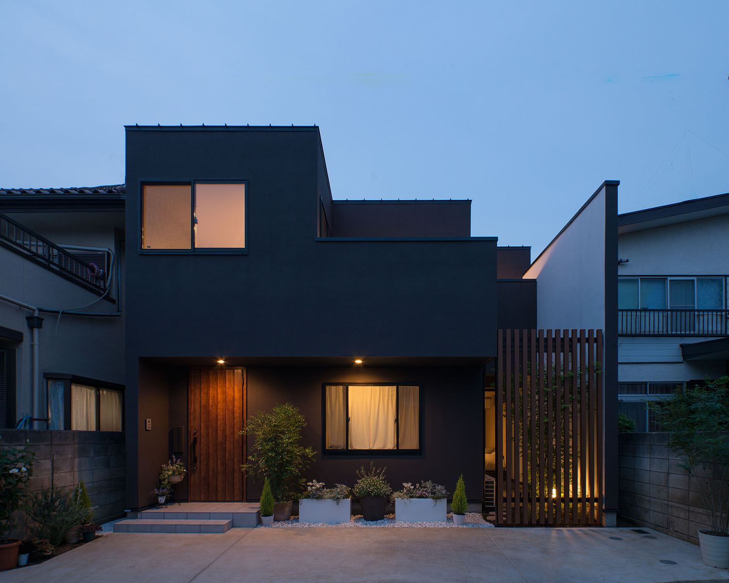 ブラウンの外壁に木材がアクセントになった住まいが照明に照らされる様子・デザイン住宅 注文住宅・デザイン住宅建築実例_『CASE453 brun』_外観