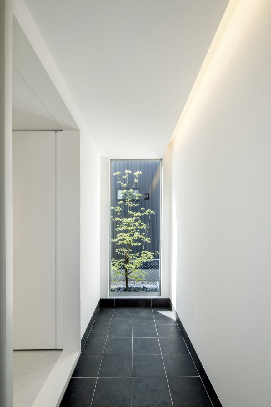 突き当りに植栽が見える窓がある黒いタイルの玄関・デザイン住宅 注文住宅・デザイン住宅建築実例_『CASE454 bridge』_玄関