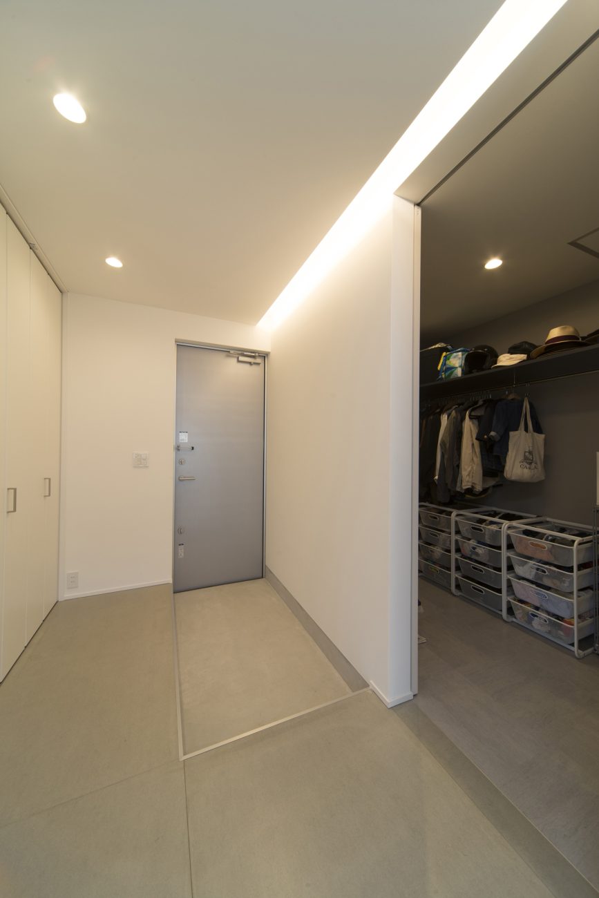 壁際に間接照明を取り付けた広いファミリークローゼットのあるスタイリッシュな玄関・デザイン住宅 注文住宅・デザイン住宅建築実例_『CASE464 無駄のない家』_玄関