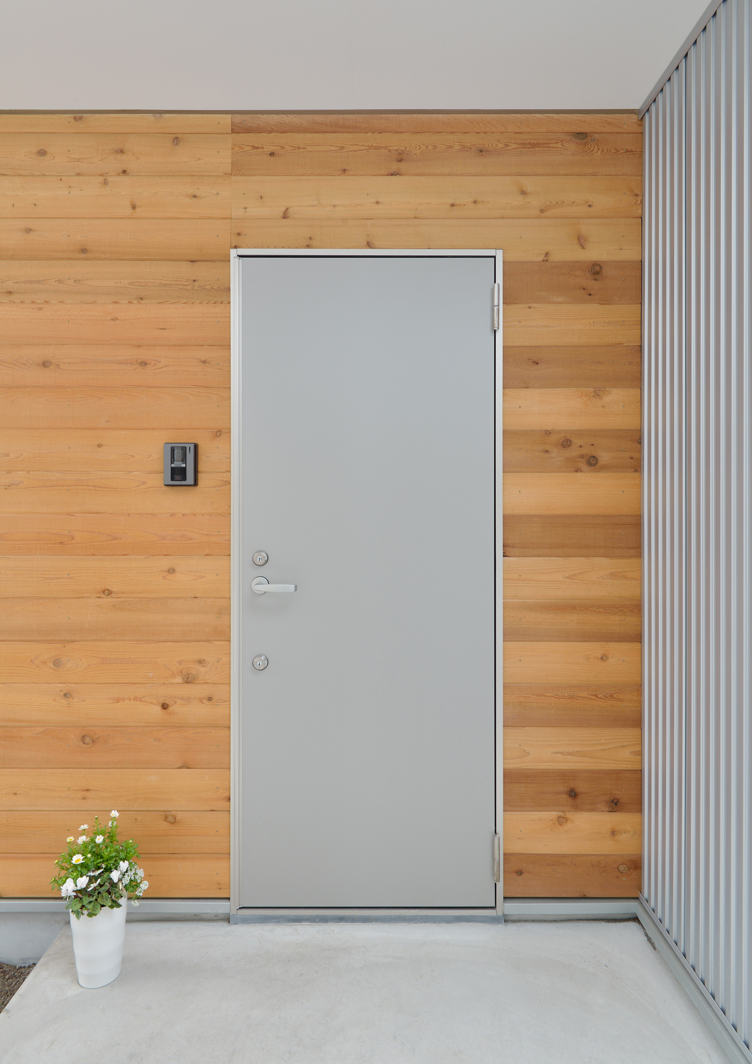 木目の外壁にシルバーのスタイリッシュな玄関扉を取り付けたエントランス・デザイン住宅 注文住宅・デザイン住宅建築実例_『CASE492 スチールと木の家』_外観