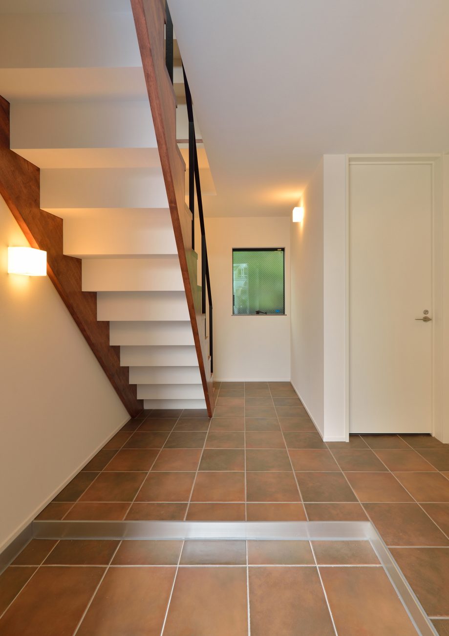 正面にスケルトン階段があるタイル床の玄関・デザイン住宅 注文住宅・デザイン住宅建築実例_『CASE494 terracotta house』_玄関