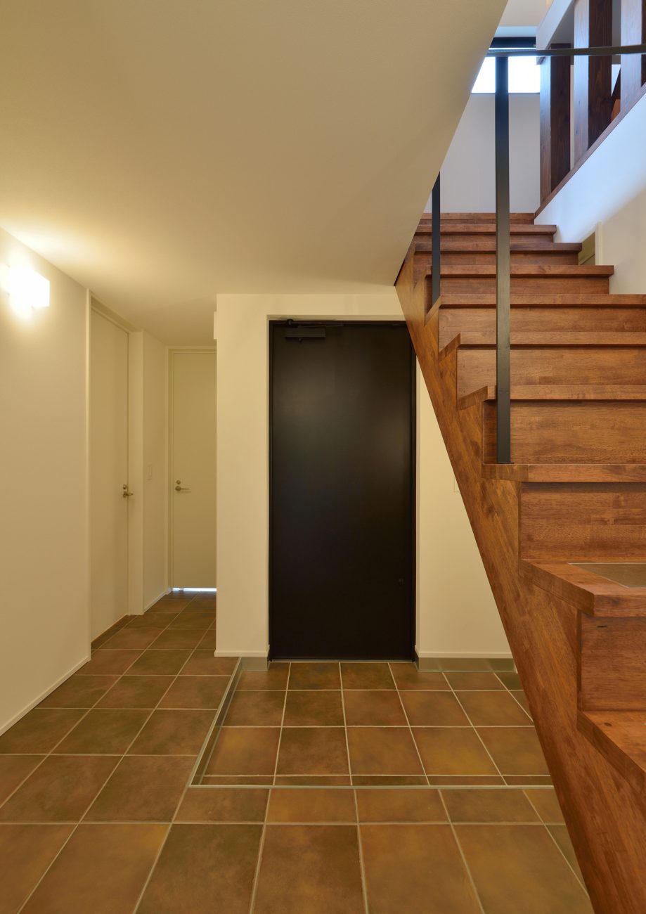 玄関と廊下に同じタイルを使った黒い扉のある玄関・デザイン住宅 注文住宅・デザイン住宅建築実例_『CASE494 terracotta house』_玄関