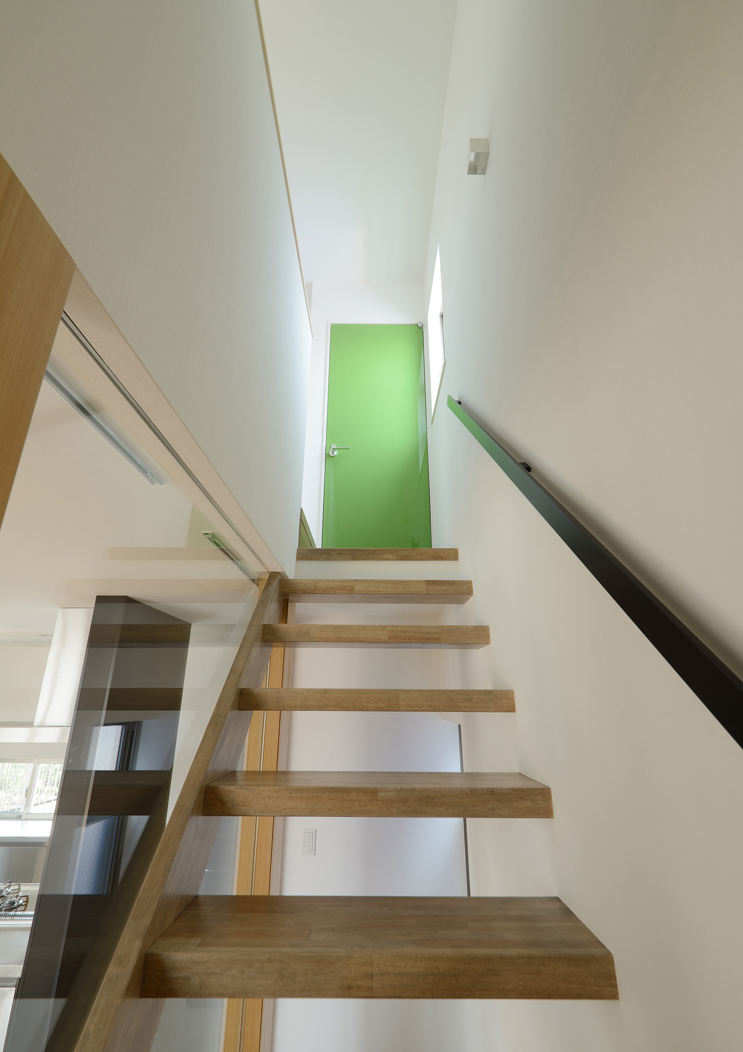木のスケルトン階段を上った先に緑色の扉がある様子・デザイン住宅 注文住宅・デザイン住宅建築実例_『CASE498 シロイイエ』_階段