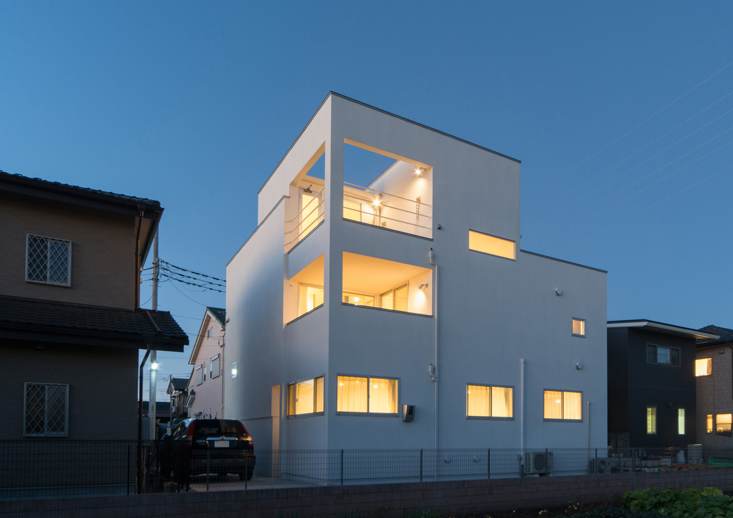 窓やバルコニーから光が漏れる白いキューブ状の家・デザイン住宅 注文住宅・デザイン住宅建築実例_『CASE504 中庭と３つのテラスのある家』_外観