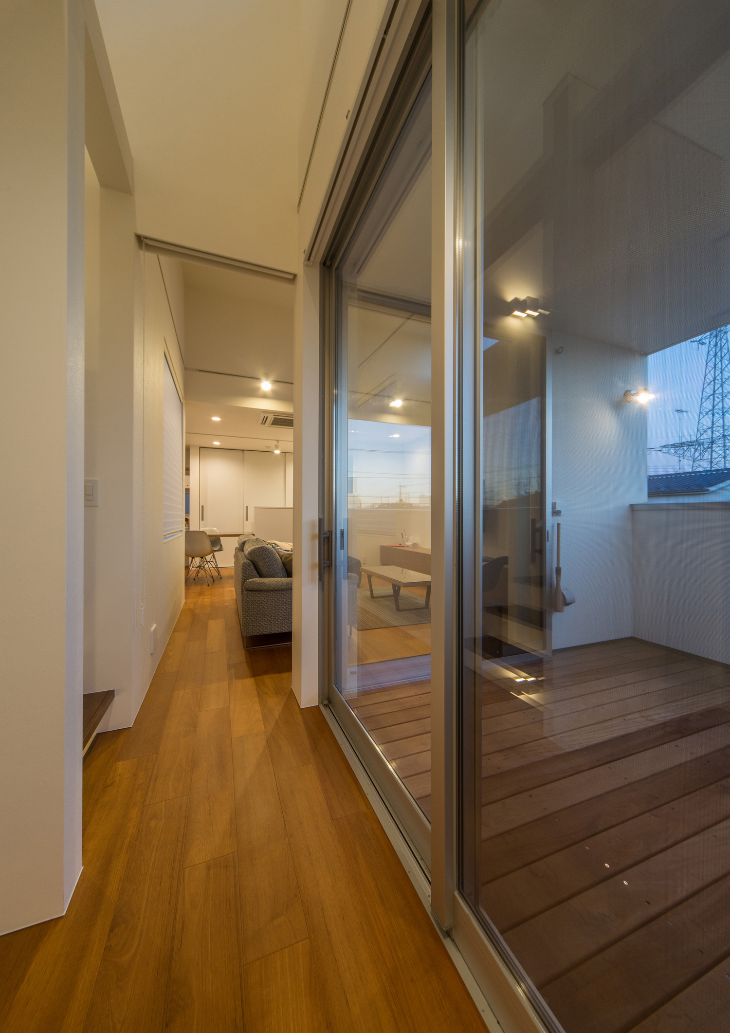 壁に照明を取り付けたバルコニーが見えるLDK・デザイン住宅 注文住宅・デザイン住宅建築実例_『CASE504 中庭と３つのテラスのある家』_廊下