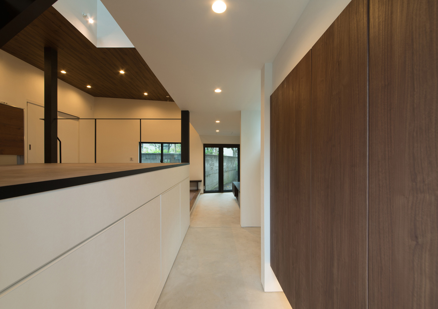 突き当りに窓がある木の扉付きのシューズボックスを設けた土間玄関・デザイン住宅 注文住宅・デザイン住宅建築実例_『CASE507 重なる家』_玄関