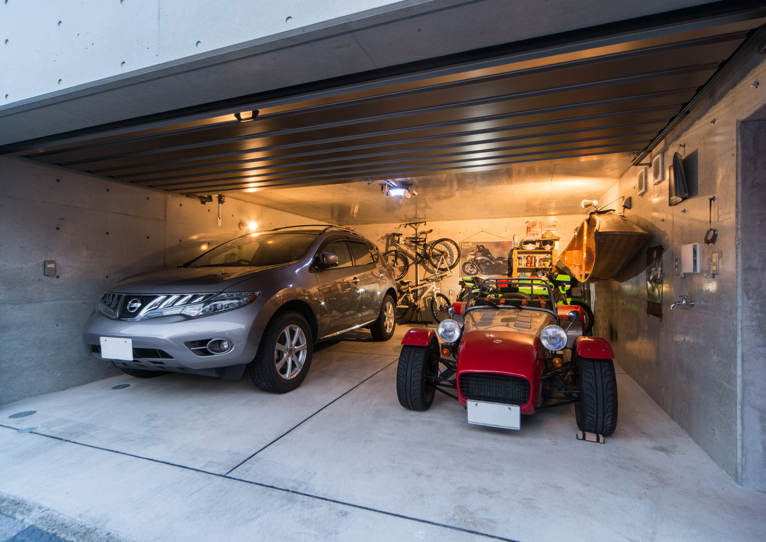 赤いスポーツカーとシルバーの車が収納されたコンクリート打ち放しのビルトインガレージ・デザイン住宅 注文住宅・デザイン住宅建築実例_『CASE511 高台のガレージハウス』_ガレージ