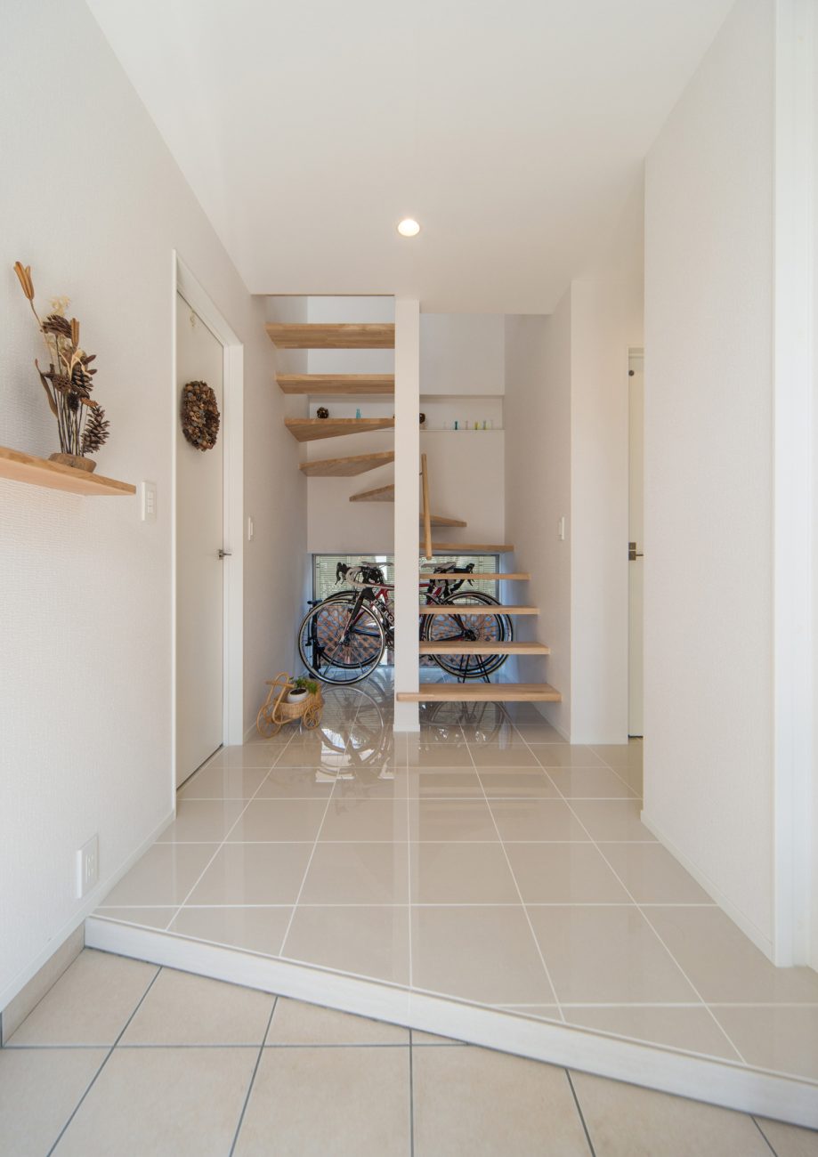 正面に木のスケルトン階段と自転車の収納スペースがあるタイル床の玄関・デザイン住宅 注文住宅・デザイン住宅建築実例_『CASE511 高台のガレージハウス』_玄関