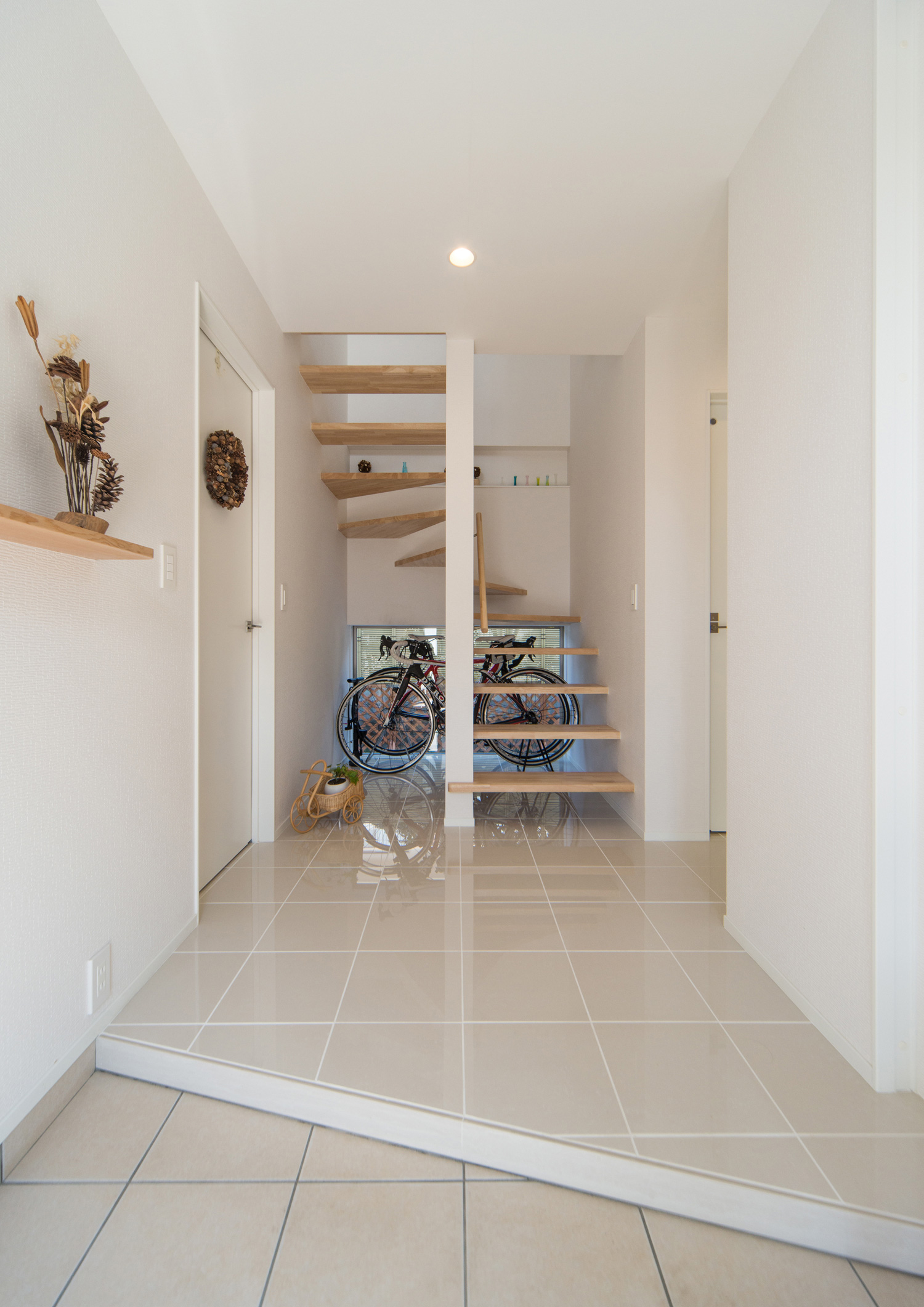 正面に木のスケルトン階段と自転車の収納スペースがあるタイル床の玄関・デザイン住宅 注文住宅・デザイン住宅建築実例_『CASE511 高台のガレージハウス』_玄関